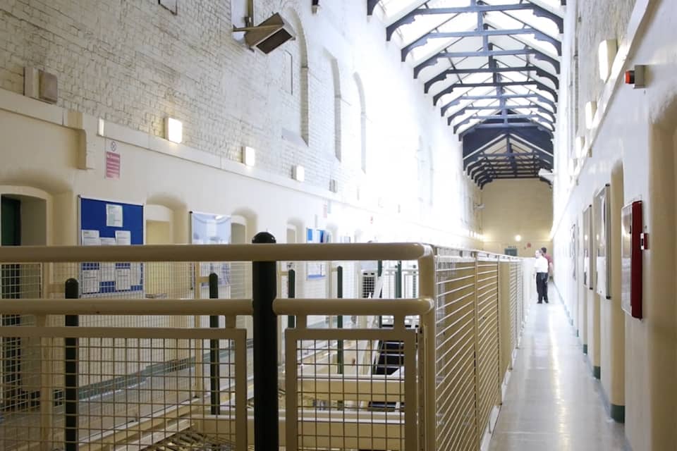 A hallway of a prison cell with a metal railing.